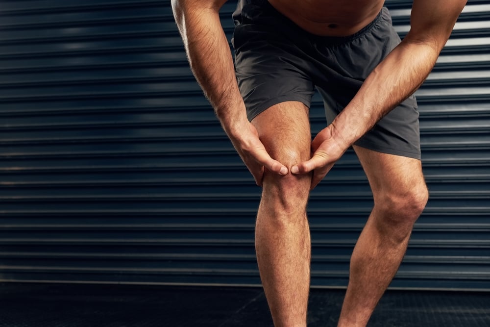 injured,,man,or,athlete,holding,knee,against,dark,background,for